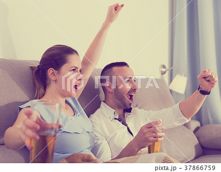 Young female and her husband are faning in time watching football 37866759