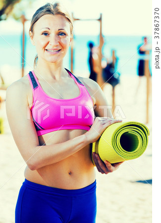 Woman standing with gymnastic mat 37867370