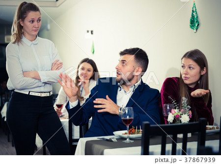 Young woman is dissatisfied in time her boyfriend is talking with woman in restaurante Young woman is dissatisfied in time her boyfriend is talking with woman in restaurante 37867939