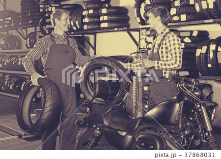 Two male professionals standing with new tires 37868031