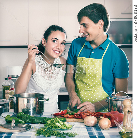 Couple at kitchen with vegetables at the table. 37868133