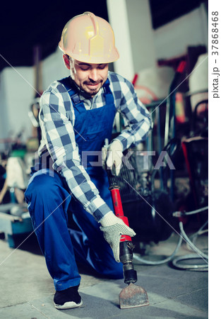Male worker using jackhammer for construction work 37868468