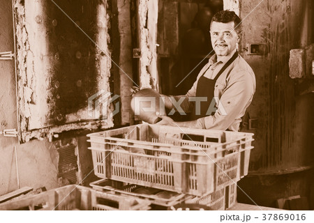 Cheerful craftsman carrying fresh baked black glazed vessel Cheerful craftsman carrying fresh baked black glazed vessel 37869016