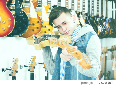 Male teenager examining electric guitars 37870301