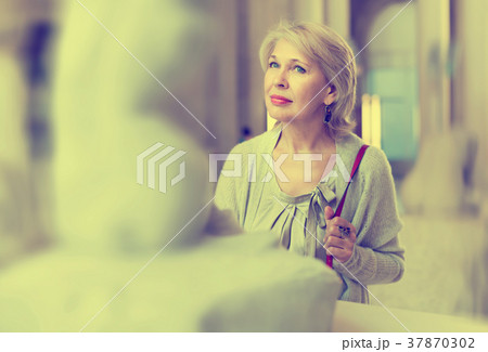 Adult female looking at artwork sculpture in the museum indoors Adult female looking at artwork sculpture in the museum indoors 37870302