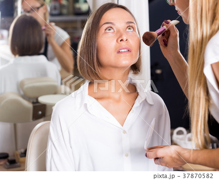 female makeup artist applying cosmetics for woman 37870582