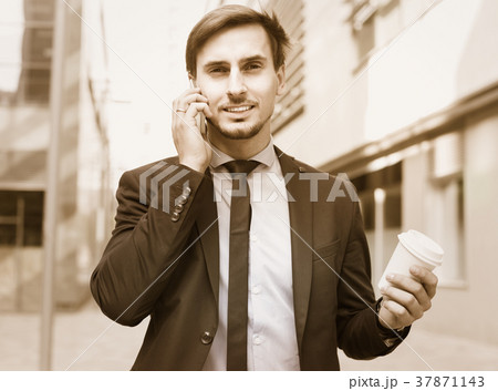 Smiling man worker talking on the phone with coffee Smiling man worker talking on the phone with coffee 37871143