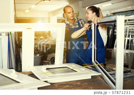 Worker helping female in work of assembling pvc windows Worker helping female in work of assembling pvc windows 37871231