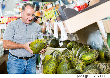 Nice man is choosing ripe melon in the store 37871448
