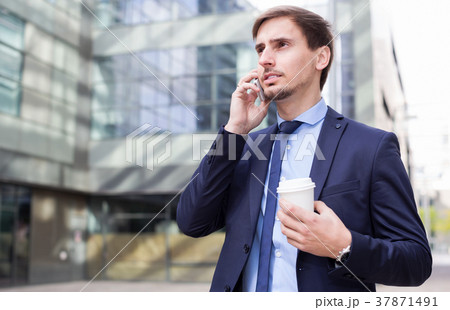 Businessman talking on the phone with coffee Businessman talking on the phone with coffee 37871491