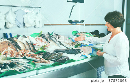 Mature woman selecting cooled fish at fishery Mature woman selecting cooled fish at fishery 37872068