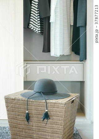 Black hat on basket with cloths hanging in closet 37877213
