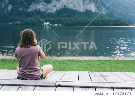 Woman sitting back on pier at lakeside 37878372
