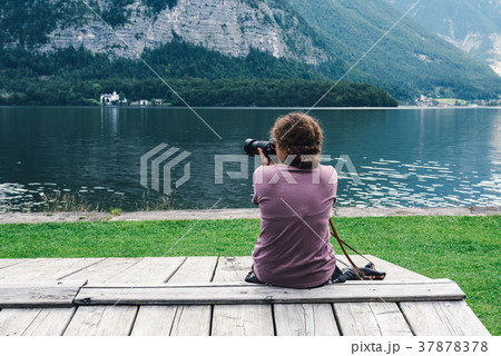 Woman sitting back on pier at lakeside 37878378