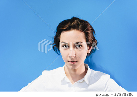オールバックの髪型をした女性 青色の背景 の写真素材