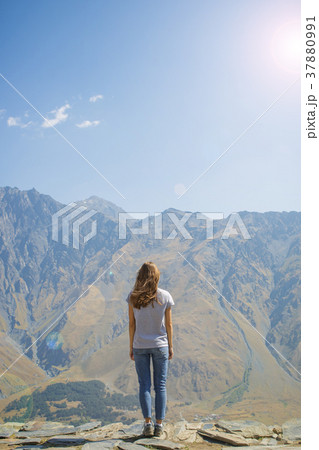 Hiker with backpack standing on top of the mountain and enjoying valley view at sunrise 37880991