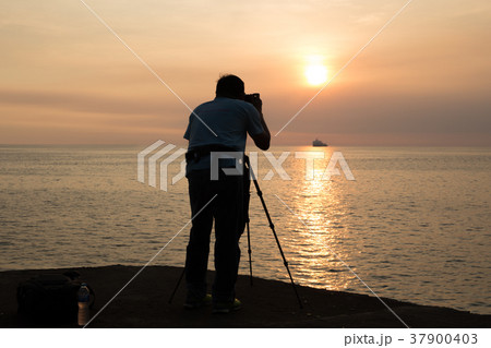 Silhouette man taking photo of ocean at and sunset 37900403