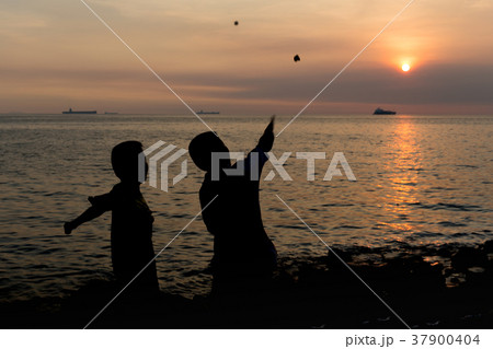 Silhouette little boy throwing a rock into the sea 37900404