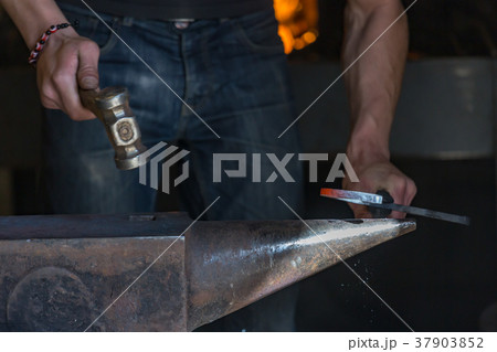 farrier making a traditional horseshoe on a forge 37903852
