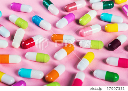different color pills on a pink background 37907331