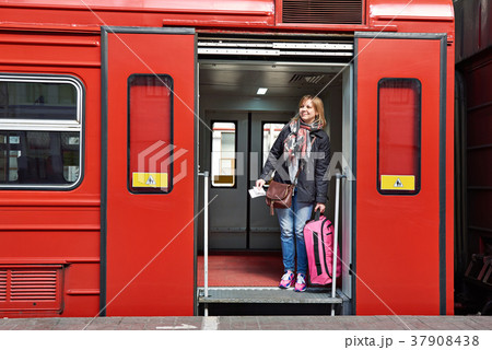 Woman tourist with suitcase coming out of train at station Woman tourist with suitcase coming out of train at station 37908438