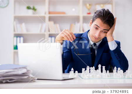Young businessman playing glass chess in office 37924891