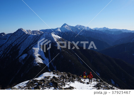 厳冬期、南アルプス仙丈ケ岳。下る登山者の彼方には日本第二の高峰、北岳がそびえています。 37925467