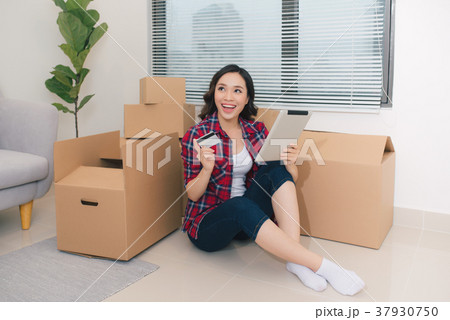 Young woman sitting on the floor holding a tablet Young woman sitting on the floor holding a tablet 37930750