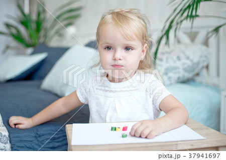 little blond child sitting at the wooden table 37941697