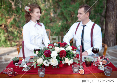 Romantic table with fresh flowers and candles with couple in love on background. 37942425