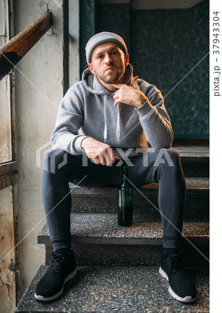 Male robber with knife sitting on the stairs Male robber with knife sitting on the stairs 37943304