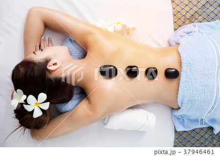 Hot stone on back of pretty woman in spa room 37946461