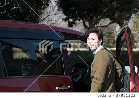 車のドアを開ける若い男性の写真素材