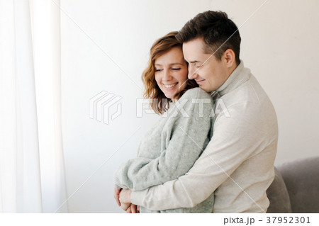 Cute couple hugging and smiling in their home Cute couple hugging and smiling in their home 37952301