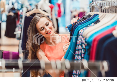 Woman browsing through dresses on rack in fashion Woman browsing through dresses on rack in fashion 37958490