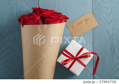 red roses bouquet on blue wood table with gift box 37964738