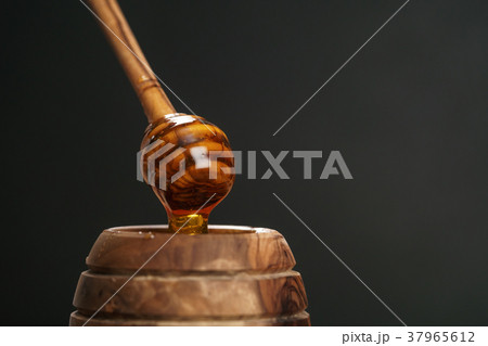 organic honey drips from wooden dipper in jar 37965612