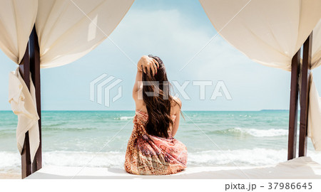 Woman sitting in beach bed looking at the sea Woman sitting in beach bed looking at the sea 37986645