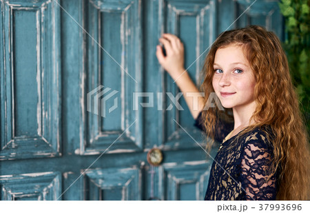 Red-haired little girl in front of blue door Red-haired little girl in front of blue door 37993696