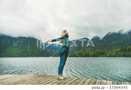 Female traveller standing at mountain lake coast 37994345