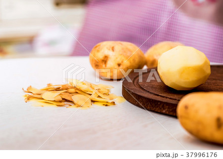 Raw potatoes and peels on table close 37996176