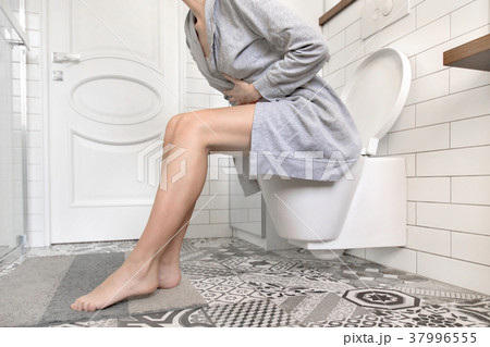 Woman sitting on toilet holding her stomach 37996555
