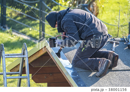 Roofer repairing the metal facing by painting Roofer repairing the metal facing by painting 38001156