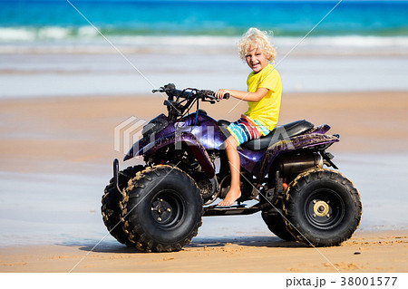 Child on quad bike at beach. All-terrain vehicle. 38001577