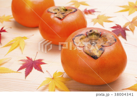 木のテーブルの上の柿と紅葉したカエデの葉 38004341