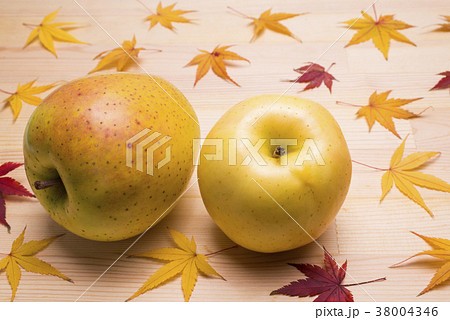 木のテーブルの上のリンゴと紅葉したカエデの葉の写真素材