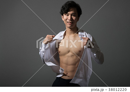 シャツを脱ぐ筋肉質の日本人男性の写真素材