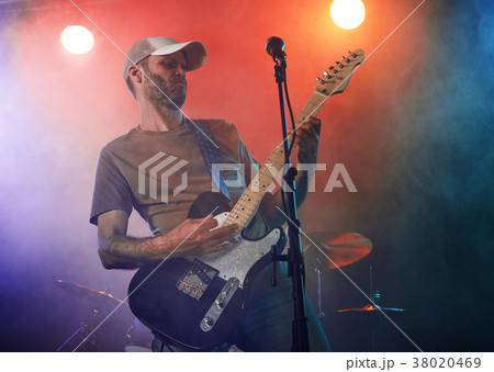 The guitarist performs on stage. 38020469