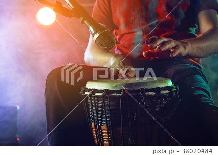 The musician plays the bongo on stage. 38020484