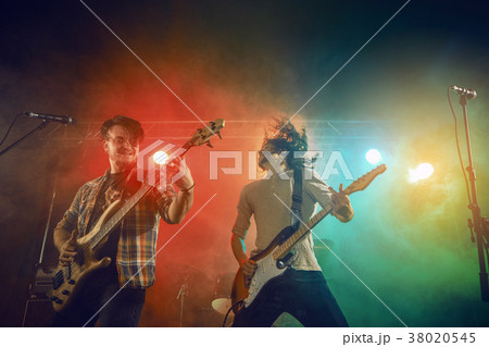 Rock band performs on stage. Guitarist, bass guitar and drums. Rock band performs on stage. Guitarist, bass guitar and drums. 38020545